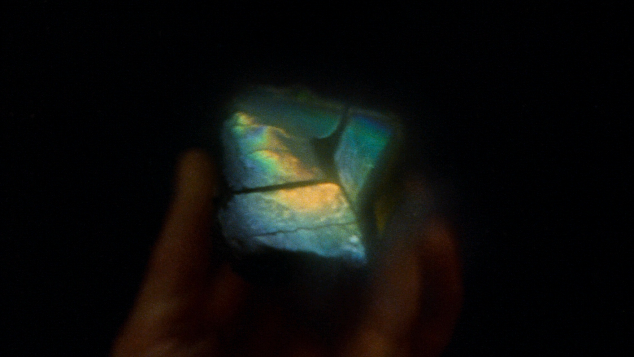 A raw labradorite fragment held in a hand