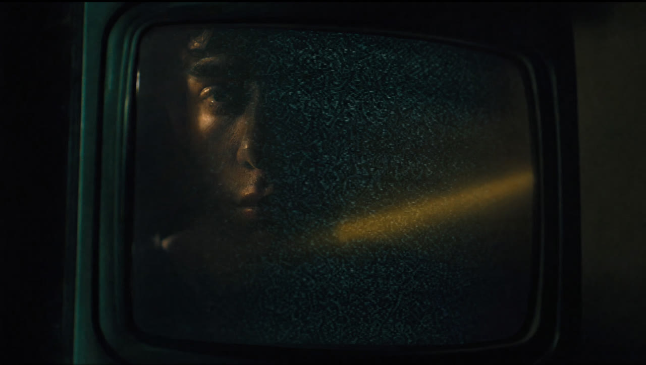 The reflection of a face in a television showing white noise